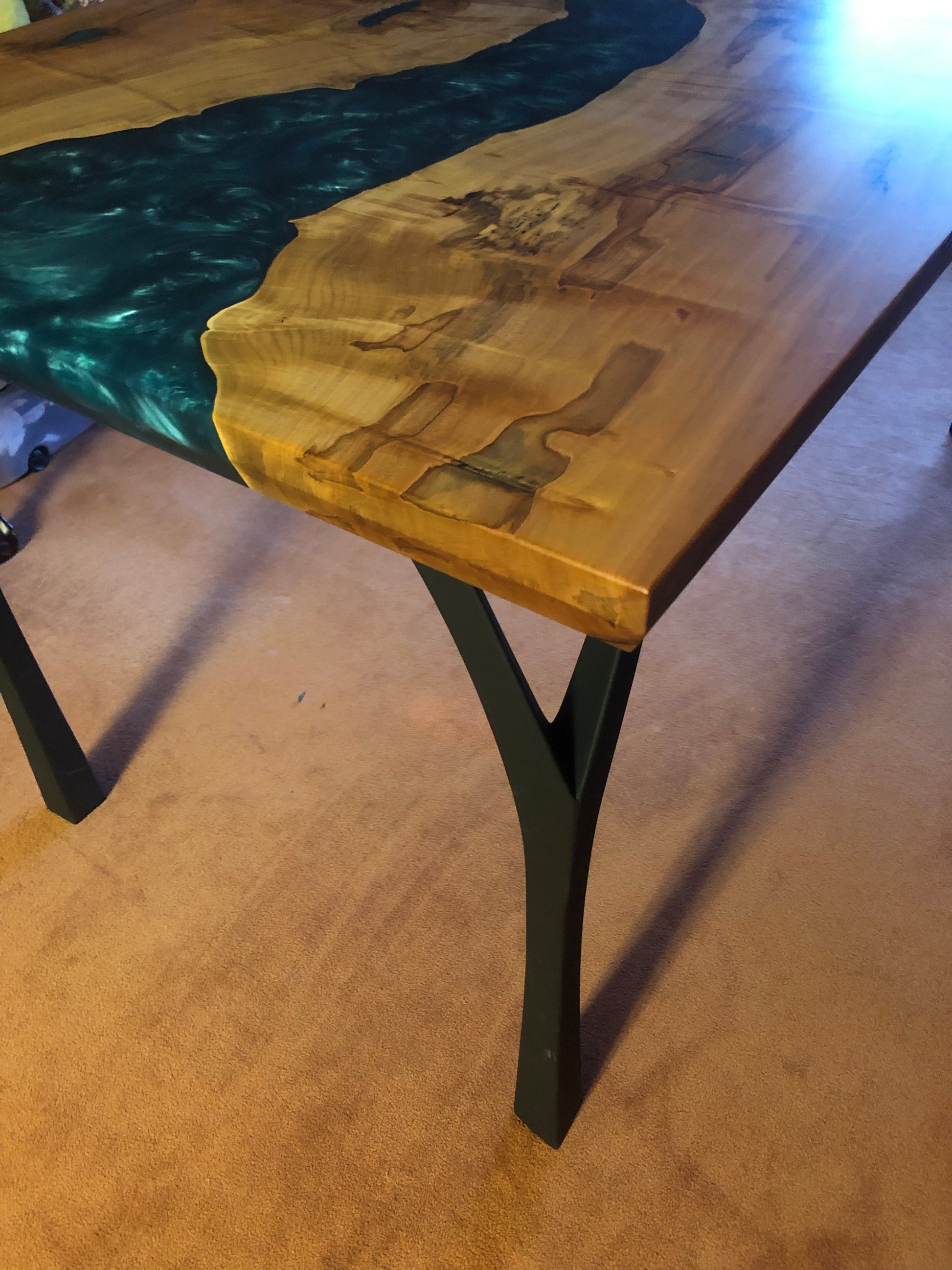 Close up of finish and legs of dark blue epoxy river table