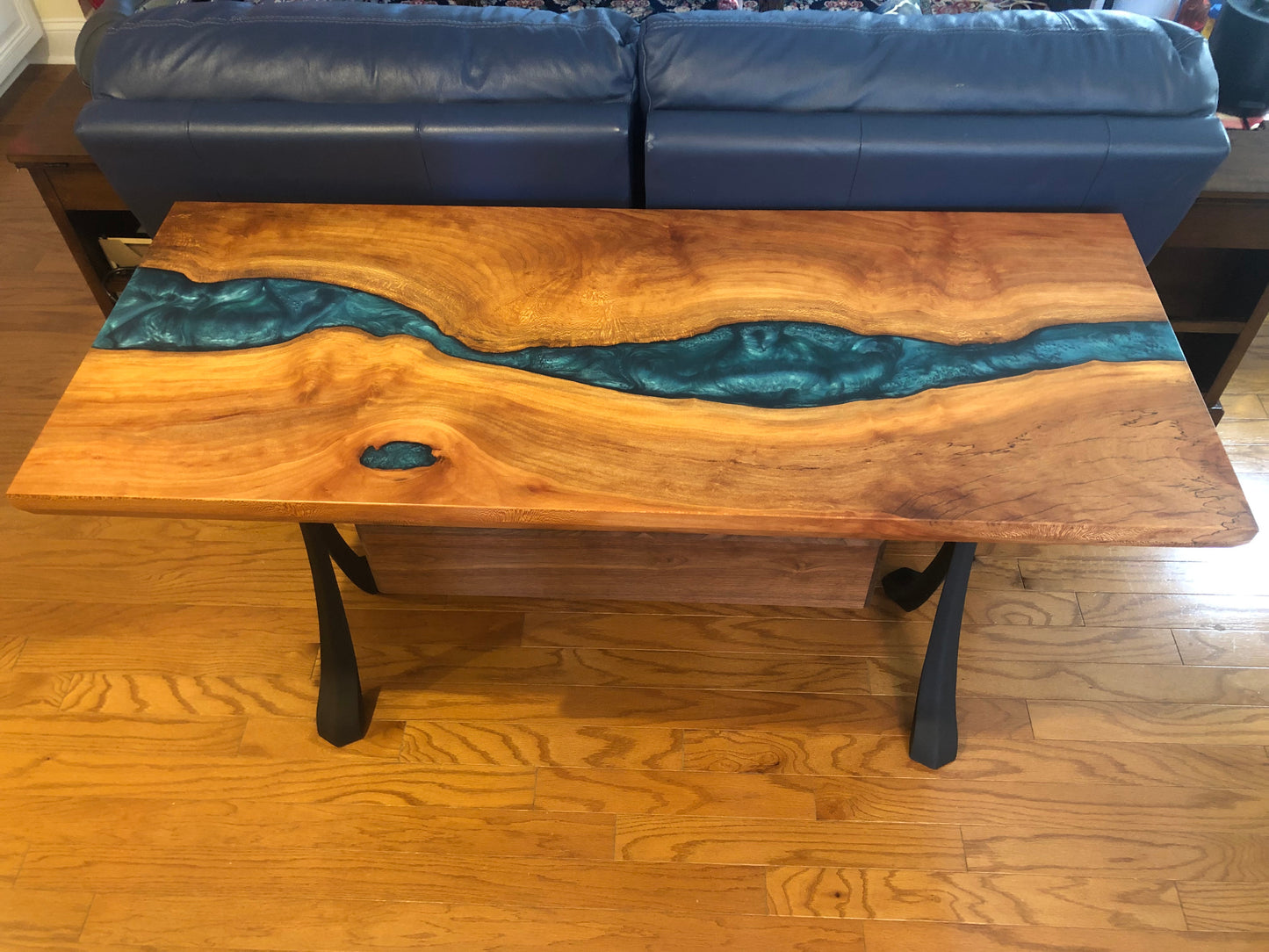 Top view of blue epoxy river table behind couch